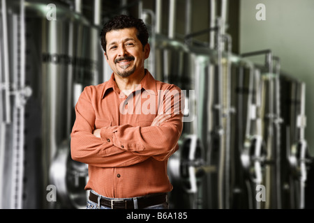 Hispanic manager standing near vats in factory Stock Photo