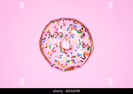 Doughnut with pink frosting and sprinkles on pink background Stock Photo