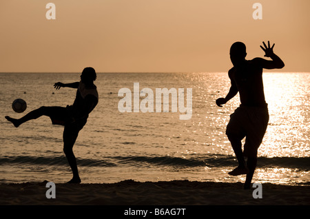 Jamaica Negril Silhouette of young men playing soccer along Caribbean Sea Stock Photo