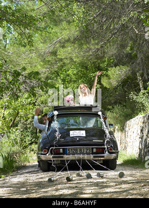 Bride and groom waving from wedding car Stock Photo