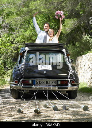 Bride and groom waving from wedding car Stock Photo