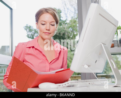 Female looking in a folder at her desk Stock Photo