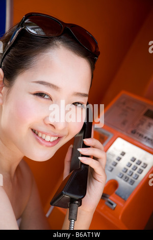 Young woman using public phone Stock Photo
