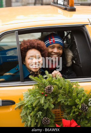 African couple riding in taxi with Christmas wreath Stock Photo