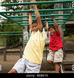 Asian boys crossing monkey bars on playground Stock Photo