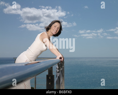 Portrait of woman leaning on railing and smiling Stock Photo