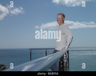 Portrait of man leaning against railing and smiling Stock Photo