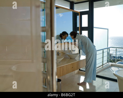 Side profile of woman washing her face in sink Stock Photo