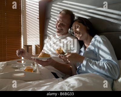 Couple having breakfast on bed and smiling Stock Photo