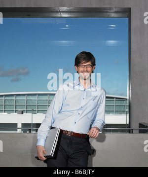 Portrait of businessman leaning against wall and smiling Stock Photo