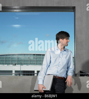 Businessman leaning against wall and smiling Stock Photo