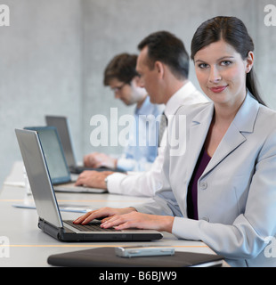Portrait of businesswoman using laptop and smiling with her colleagues sitting in background Stock Photo