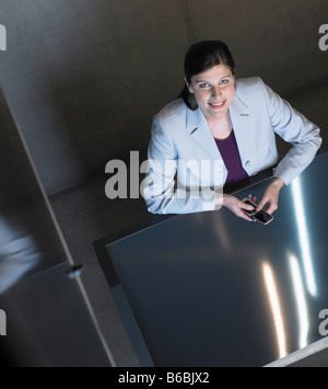 Woman sitting at table using mobile phone Stock Photo