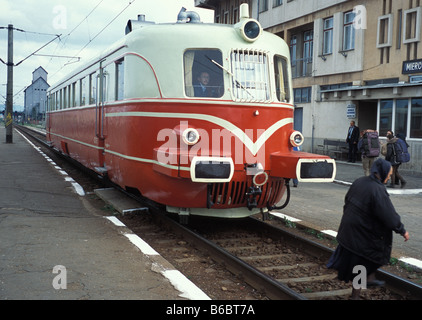 An old woman crosses the train line in the town of Miercuria Ciuc infront of a train used by the head of romania railways Stock Photo