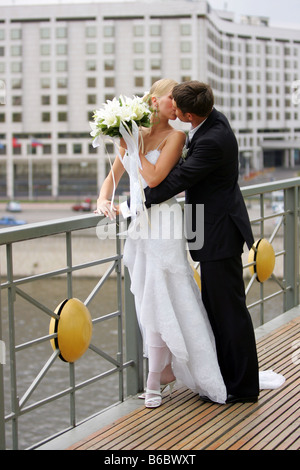 Newlywed couple kissing in urban scene water in background Stock Photo