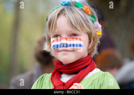Girl with Dutch Flag face paint on Kingsday (Queensday) Kings Day, the King's Birthday Celebrations in Amsterdam Holland Netherlands flag. Stock Photo