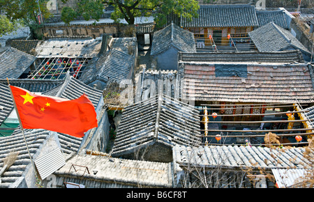 CHINA Chuandixia Flag of the Peoples Republic of China flying above the tile rooftops of traditional stone communal farmhouses Stock Photo