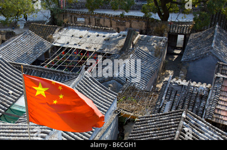 CHINA Chuandixia Flag of the Peoples Republic of China flying above the tile rooftops of traditional stone communal farmhouses Stock Photo