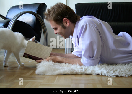 Side profile of young man playing with cat on floor Stock Photo