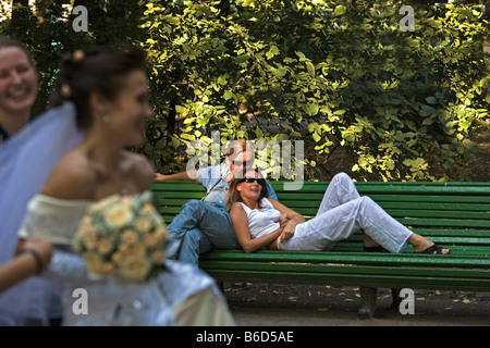 Russia, Saint Petersburg, Summer Garden ( Letnij Sad ). Young couple on bench and passing bride. Stock Photo