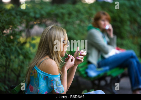 Russia, Saint Petersburg, Summer Garden ( Letnij Sad ). Young woman putting lipstick on lips. Stock Photo