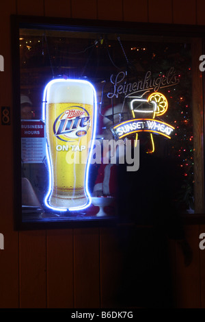 A man dressed up as Santa Claus sitting in the window of a bar with Leinenkugels and Miller Lite Beer signs in Wisconsin Stock Photo