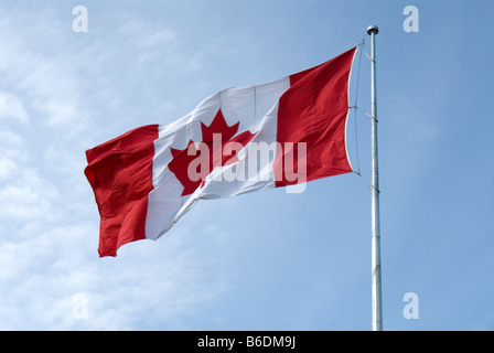 A Large Canadian Maple Leaf Flag Flying in the Wind Against a Blue Sky Stock Photo