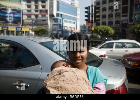 A beggar girl holding a baby in traffic Dhaka Stock Photo
