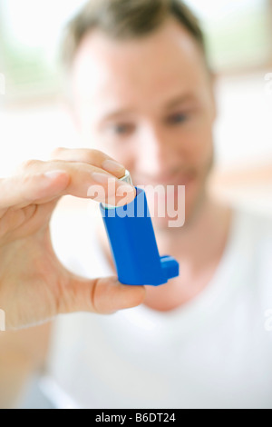 Man using an inhaler to treat an asthma attack Stock Photo