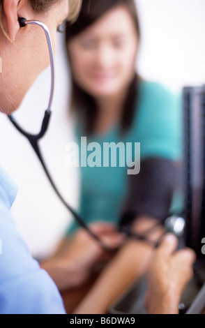 Blood pressure measurement. General practice doctor using a sphygmomanometer and stethoscope to measure a patient's BP. Stock Photo