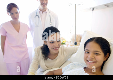 Teenage hospital patient. Doctor and nurse standing by a patient and her mother.