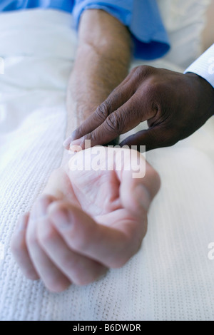 Checking pulse. Doctor using his fingers to feel a patient's pulse. Stock Photo