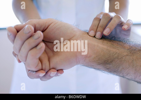 Checking pulse. Nurse using his fingers to feel a patient's pulse. Stock Photo