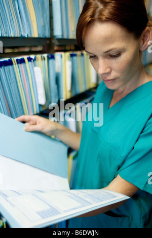 Medical records. Nurse reading a medical record in a store room. Stock Photo