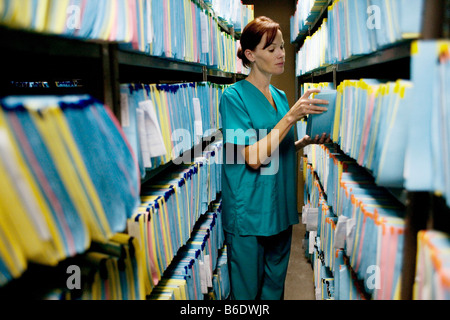 Medical records. Nurse checking a medical record in a store room. Stock Photo