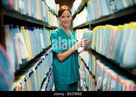 Medical records. Nurse checking a medical record in a store room. Stock Photo