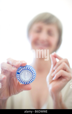 Hormone replacement therapy pills.Woman holding a circular pill dispenser and a hormone replacement therapy pill. Stock Photo