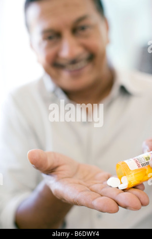 Painkillers. Man pouring painkilling pills into the palm of his hand. Stock Photo