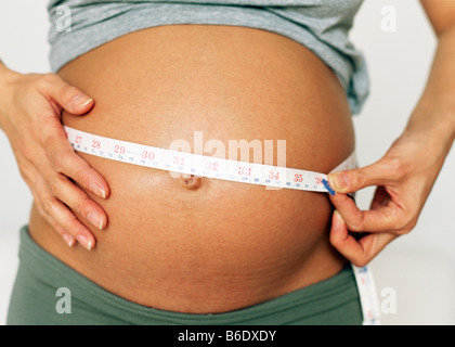 Pregnant woman measuring her swollen abdomen Stock Photo