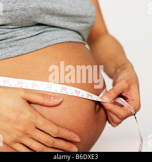 Pregnant woman measuring her swollen abdomen Stock Photo