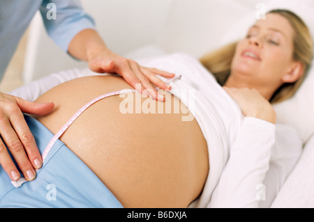 Obstetric examination. Midwife measuring the size of a pregnant woman's abdomen. Stock Photo