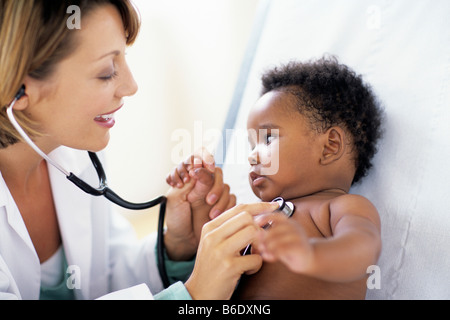 Paediatric examination. Health of a 12-week-old baby girl being checked by the use of a stethoscope. Stock Photo