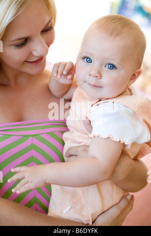 Teenage mother and baby. Young mother holding her 10 month old daughter. Stock Photo