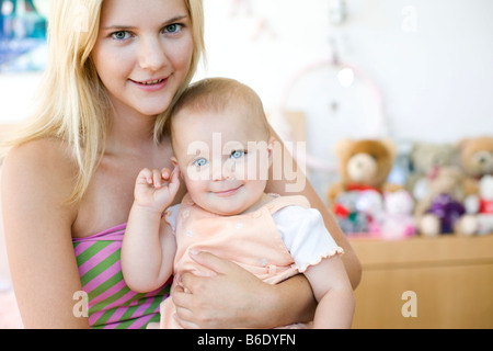 Teenage mother and baby. Young mother holding her 10 month old daughter. Posed by models. Stock Photo