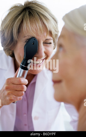 Eye examination. General practice doctor examining a 63-year-old woman's eye with an ophthalmoscope. Stock Photo