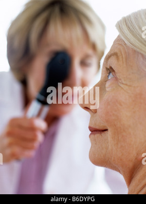 Eye examination. General practice doctor examining a 63-year-old woman's eye with an ophthalmoscope. Stock Photo