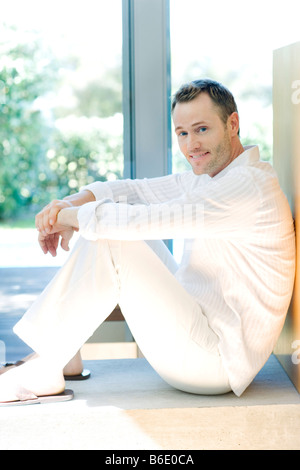 Happy man sitting on the floor bya window. Stock Photo