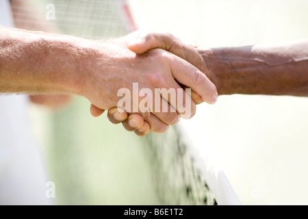 Tennis match. Two players shaking hands over a tennis net after a match. Stock Photo