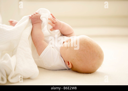 Baby girl playing with a blanketon the floor Stock Photo