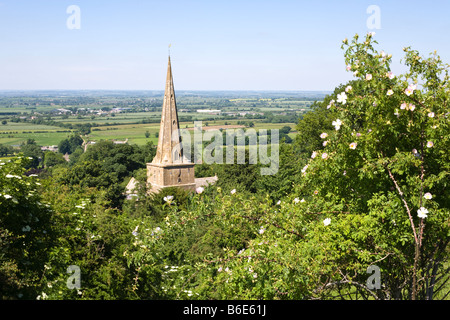 Looking across St Nicholas church in the Cotswold village of Saintbury, Gloucestershire and out across the Vale of Evesham Stock Photo